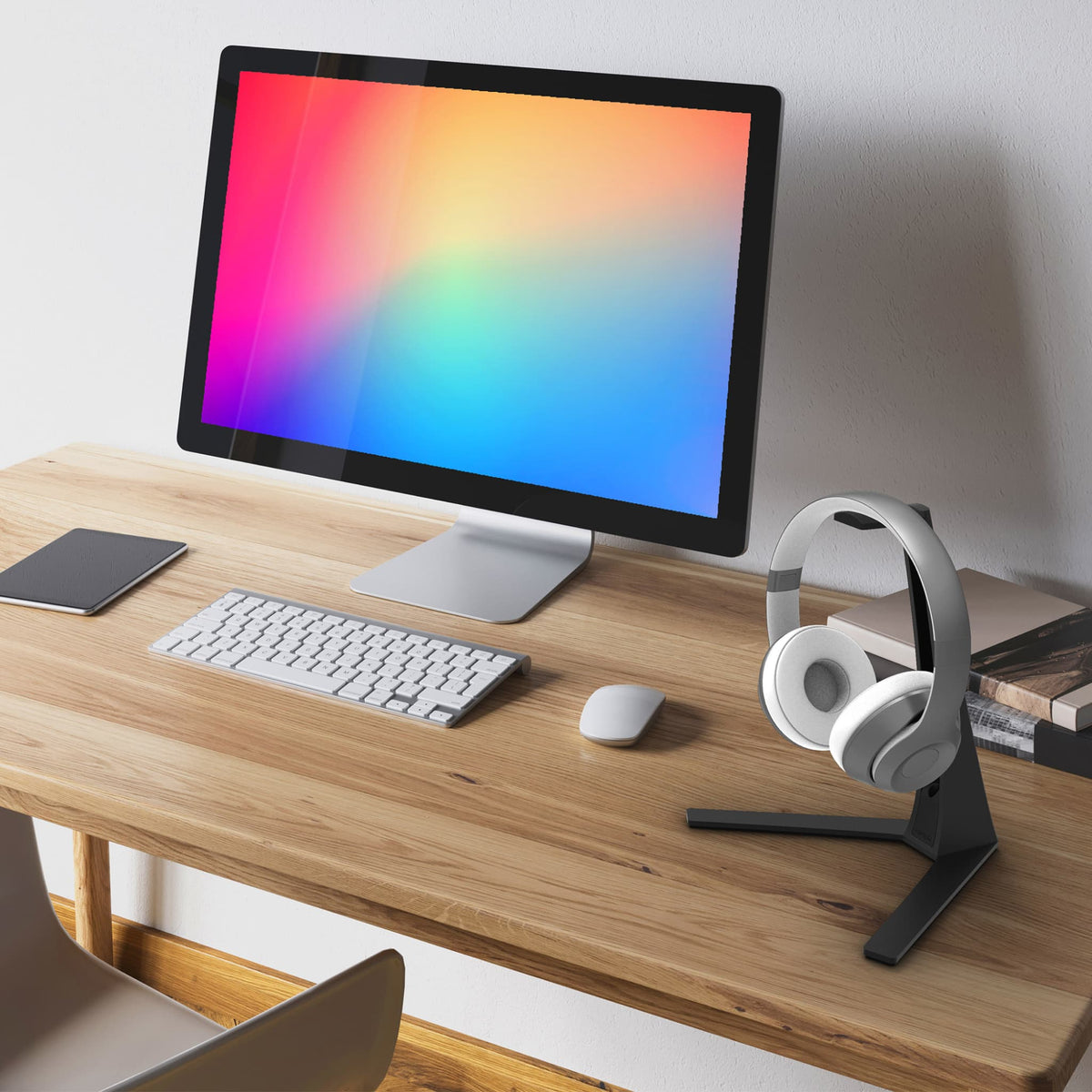A pair of over-ear headphones on a black stand on a wooden desk.