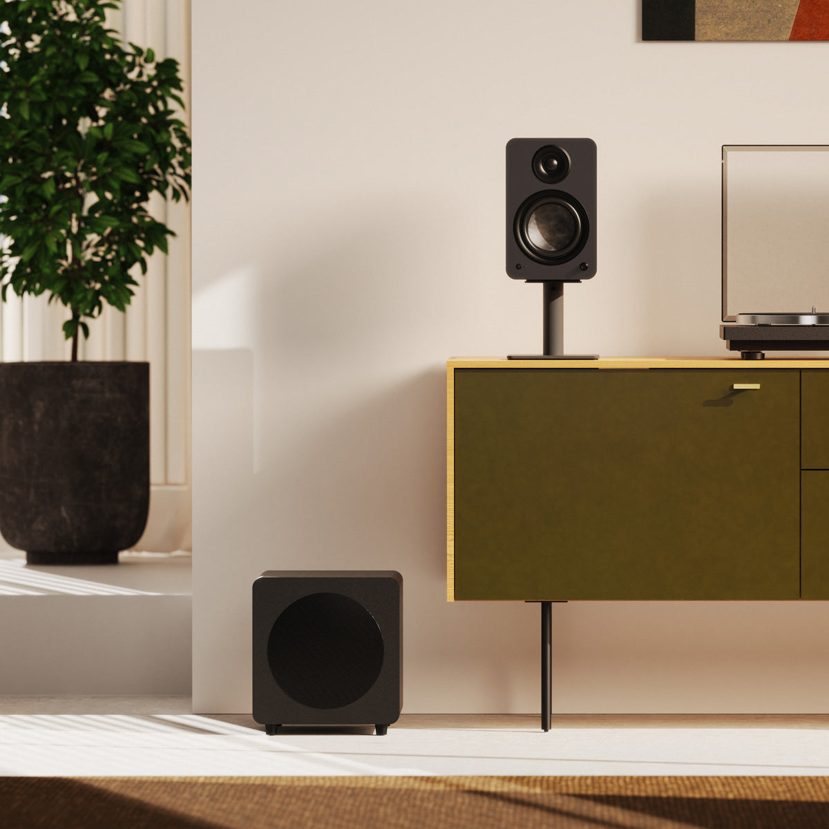 A pair of black speakers in a modern living room setting, with a Kanto Sub8 subwoofer on the floor and a speaker on a stand on a green cabinet.