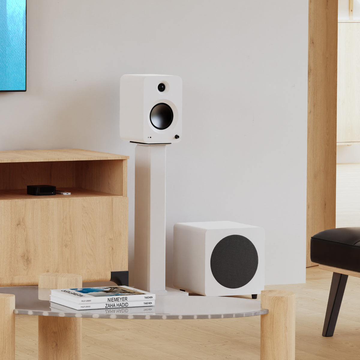A pair of white bookshelf speakers, including a tall floor-standing model and a cube-shaped subwoofer, displayed in a modern living room setting.