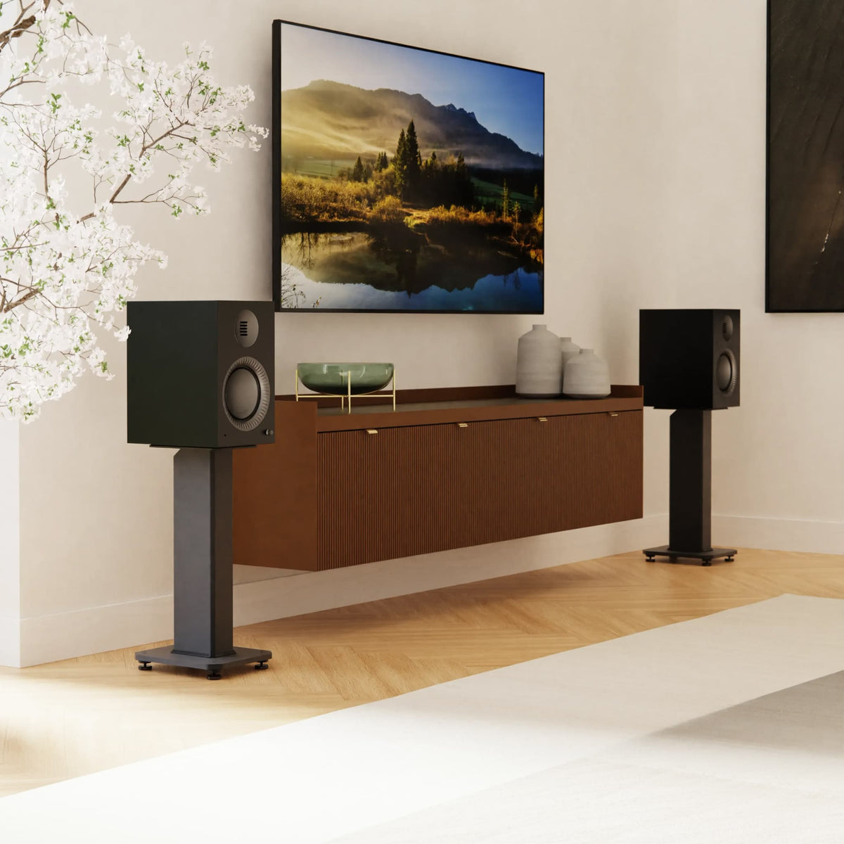 A pair of black speakers on slim stands flanking a floating wooden media console beneath a large wall-mounted TV.
