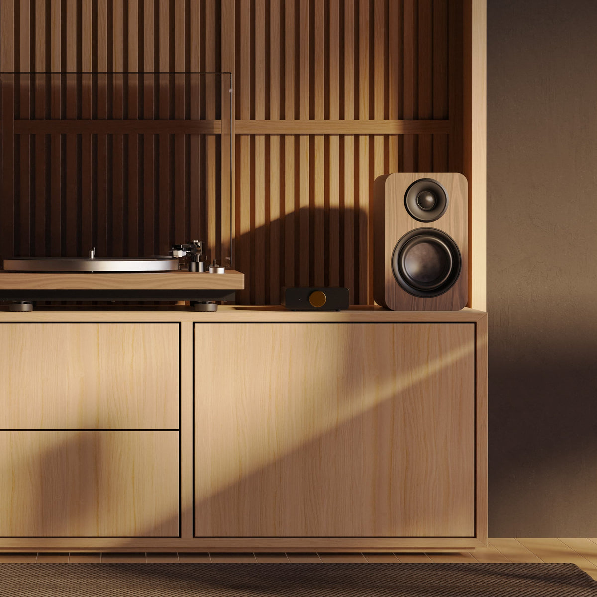 A modern wooden media console in a warm light oak finish, styled with a wood-grain speaker, a turntable, and a small speaker, set against a matching slatted wood wall with dramatic warm sunlight.